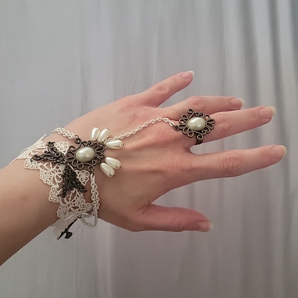 White lace and metal work bracelet with attached ring.